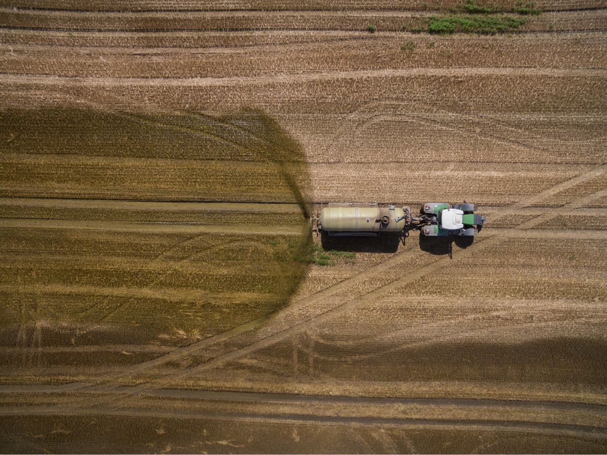 tractor with a trailer fertilizes a freshly plowed agricultural field